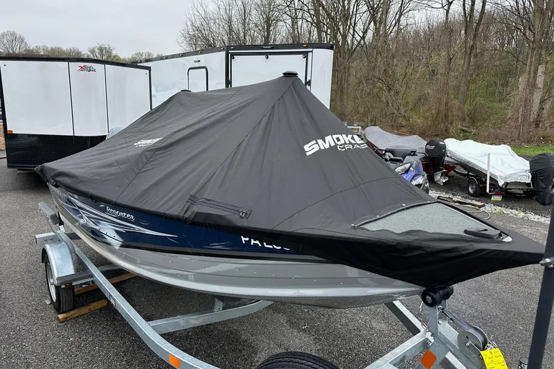Slide: The Image of 2025 Smoker Craft Resorter 151 boat covered on a trailer in a parking area. - 17