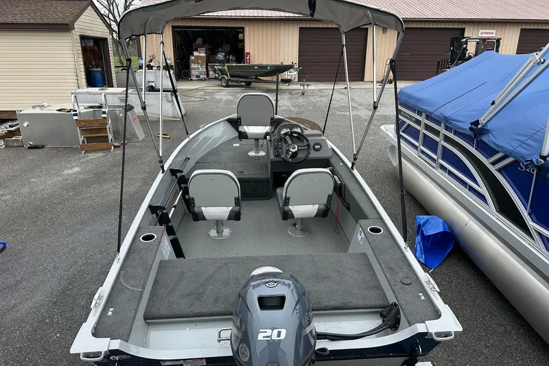 Slide: The Image of 2025 Smoker Craft Resorter 151 boat with canopy, parked outdoors. - 4