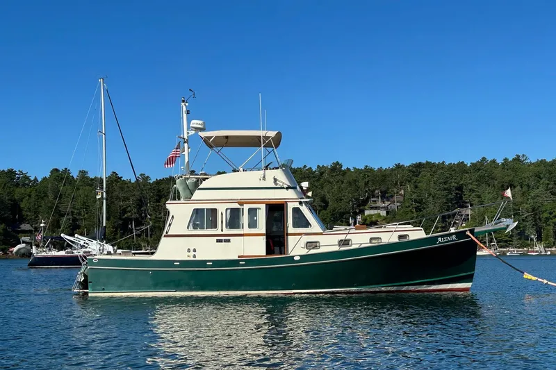 The Image of 1988 Custom Holland Wesmac-Foley Flybridge Cruiser on serene water, surrounded by lush greenery. - 0