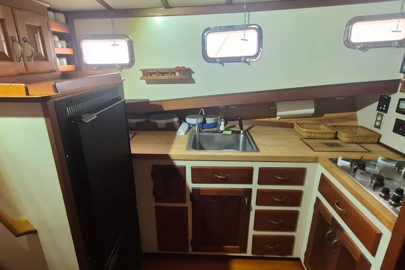 Slide: The Image of Kitchen area of 1988 Custom Holland Wesmac-Foley Flybridge Cruiser with wooden cabinets and sink. - 26