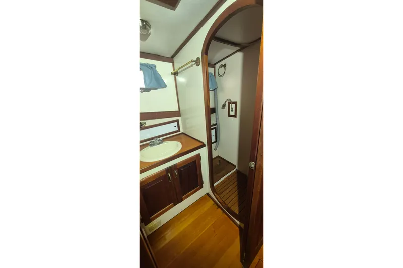Slide: The Image of Interior of 1988 Custom Holland Wesmac-Foley Flybridge Cruiser, featuring wooden cabinetry and compact bathroom. - 49