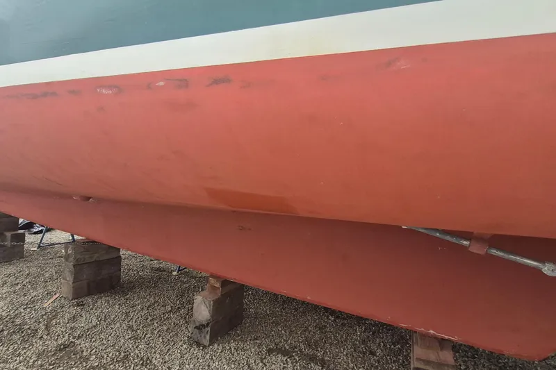 Slide: The Image of 1988 Custom Holland Wesmac-Foley Flybridge Cruiser hull on wooden blocks, gravel ground. - 98