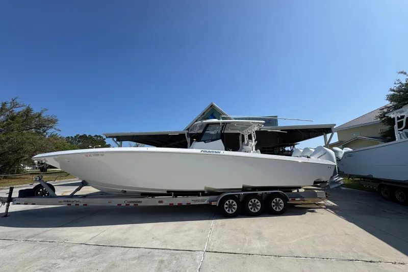 The Image of 2023 Fountain Bluewater 38 CC boat on trailer, parked outdoors under clear blue sky. - 1