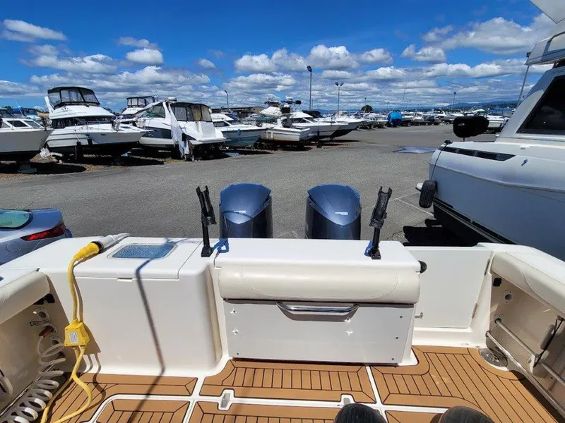 Slide: The Image of 2013 Pursuit 345 OS Offshore boat with twin engines, docked in a marina under a blue sky. - 20