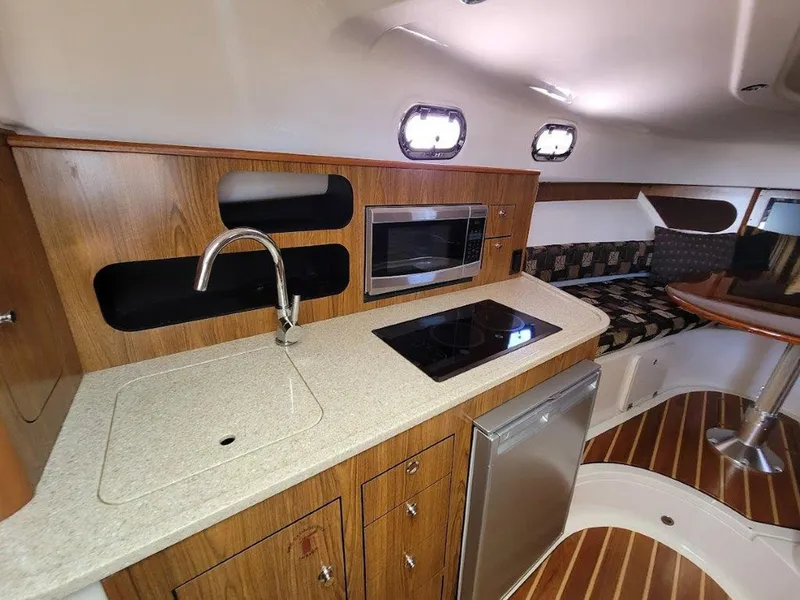 Slide: The Image of 2013 Pursuit 345 OS Offshore yacht interior with kitchenette, featuring sink, microwave, and seating area. - 29