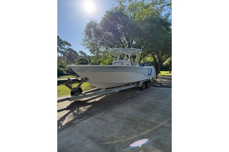 The Image of 2018 Seafox 288 Commander boat on trailer under sunny sky, surrounded by trees. - 1