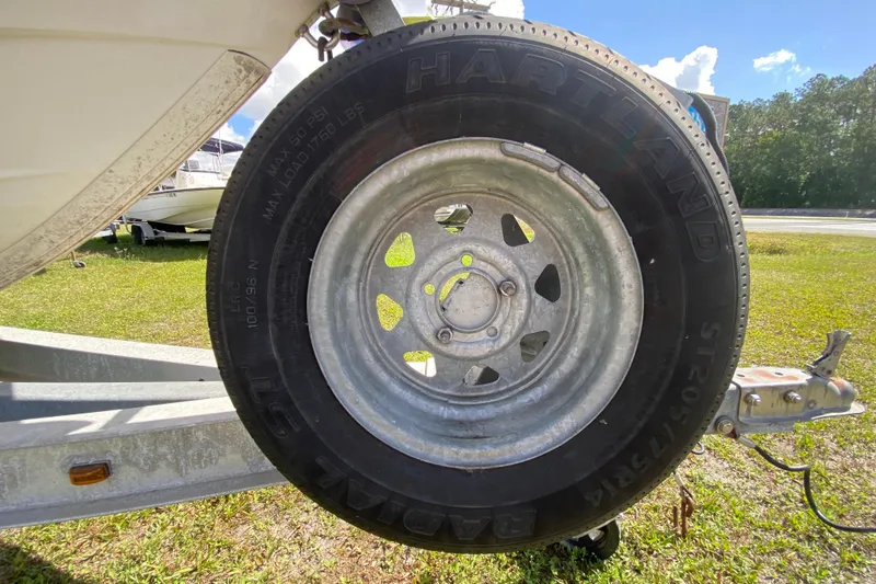 Slide: The Image of Trailer tire on a 1999 Pathfinder 2200 Tournament Edition boat, parked on grass. - 14