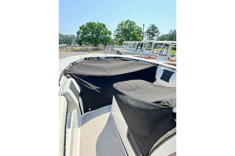 Slide: The Image of 2024 Tidewater 320 CC Adventure boat with black covers on deck, parked outdoors. - 40