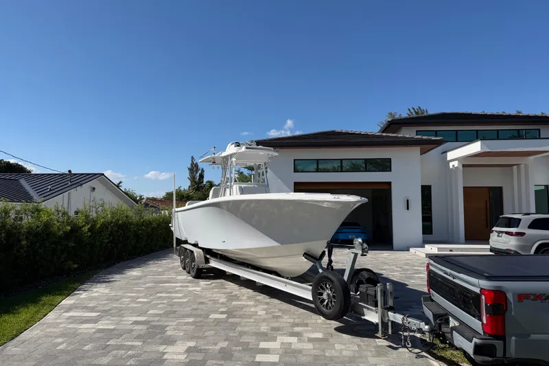 Slide: The Image of 2021 SeaVee 322Z boat on trailer in modern driveway, sunny day. - 2