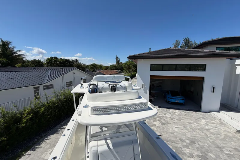 Slide: The Image of 2021 SeaVee 322Z boat parked beside a modern house under a clear blue sky. - 21
