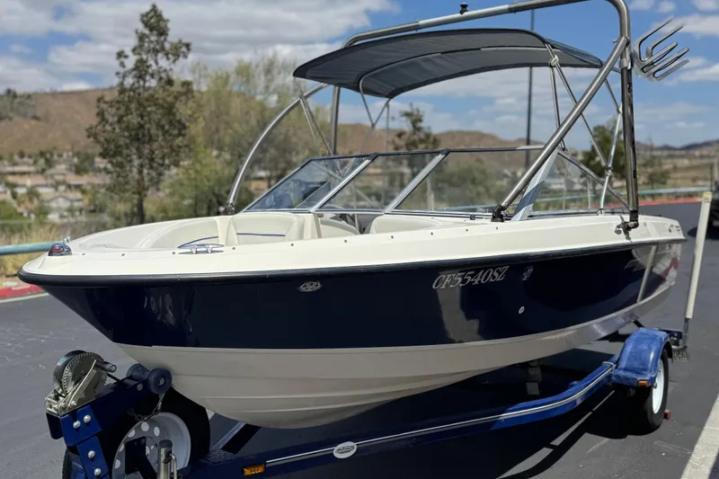 Slide: The Image of 2006 Bayliner 195 Bowrider boat on trailer, featuring sleek design and bimini top. - 3