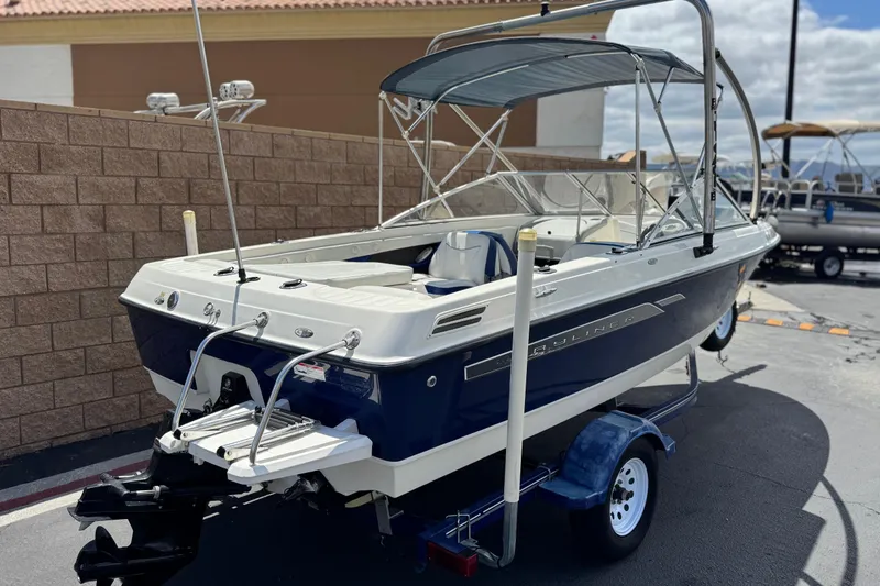 Slide: The Image of 2006 Bayliner 195 Bowrider boat on trailer, parked outdoors, featuring blue and white design. - 5