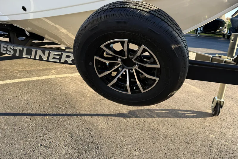 Slide: The Image of 2026 Crestliner 1850 Super Hawk trailer wheel on asphalt, showcasing sleek design. - 5