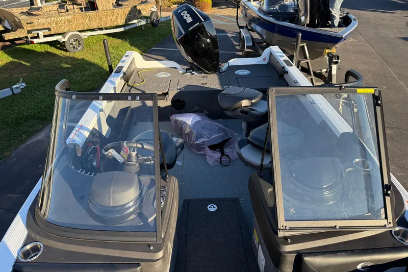 Slide: The Image of 2026 Crestliner 1850 Super Hawk boat interior with seating and windshield, parked outdoors. - 7