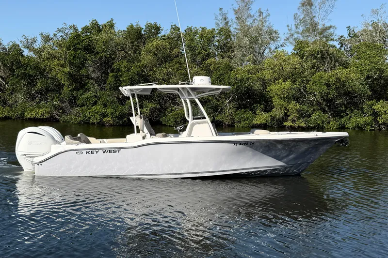 The Image of 2022 Key West 263 FS boat cruising on a calm river with lush greenery. - 0