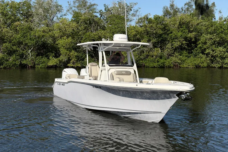 Slide: The Image of 2022 Key West 263 FS boat on calm water, surrounded by lush greenery. - 2