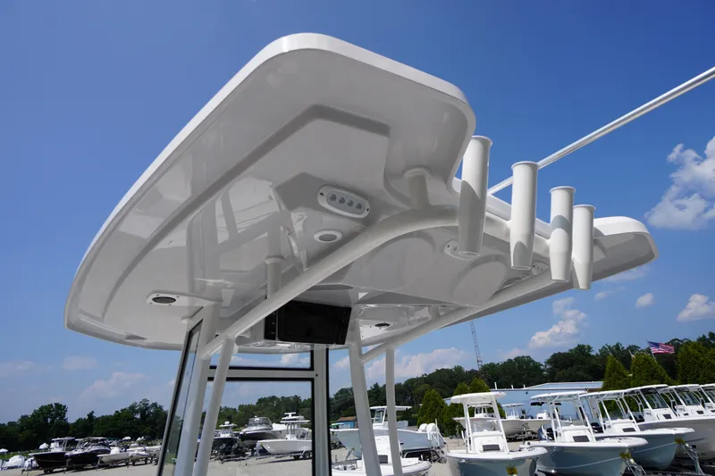 Slide: The Image of 2026 Tidewater 198 CC Adventure boat's T-top with rod holders under clear blue sky. - 40