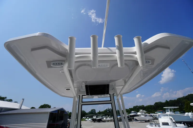 Slide: The Image of 2026 Tidewater 198 CC Adventure boat, T-top view with rod holders, under clear blue sky. - 41