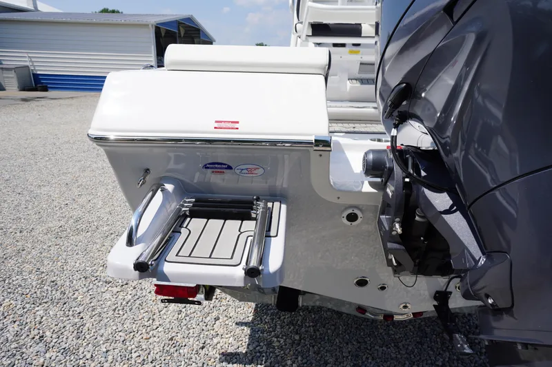 Slide: The Image of 2026 Tidewater 198 CC Adventure boat with swim platform and ladder, parked on gravel. - 48