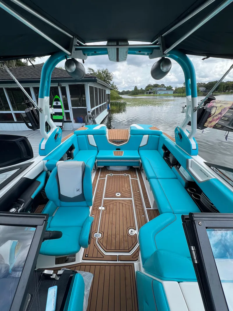 Slide: The Image of 2018 Nautique Super Air G23 boat with turquoise seating and teak flooring, docked by a lake. - 11