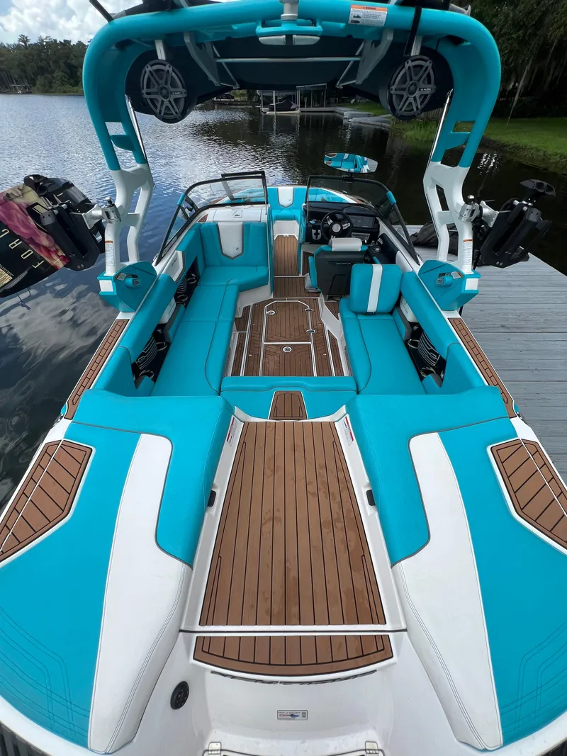 Slide: The Image of 2018 Nautique Super Air G23 boat with turquoise seating and wooden deck, docked by a lake. - 9