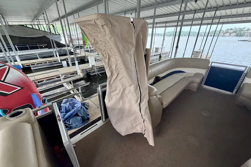 Slide: The Image of 2013 Harris Solstice 240 pontoon boat interior at dock, featuring beige seating and cover. - 29
