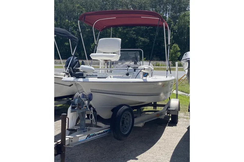 Slide: The Image of 2003 Seapro 1700 CC boat with red canopy on a trailer, parked outdoors. - 14