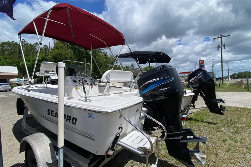 Slide: The Image of 2003 Seapro 1700 CC boat with Mercury outboard motors, parked on a trailer under a cloudy sky. - 3