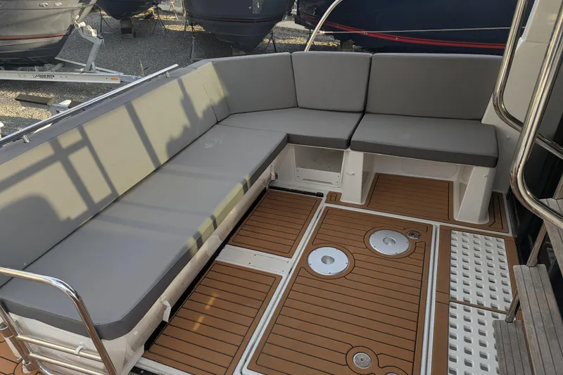 Slide: The Image of 2024 Beneteau Antares 11 Fly boat seating area with cushioned benches and teak flooring. - 7