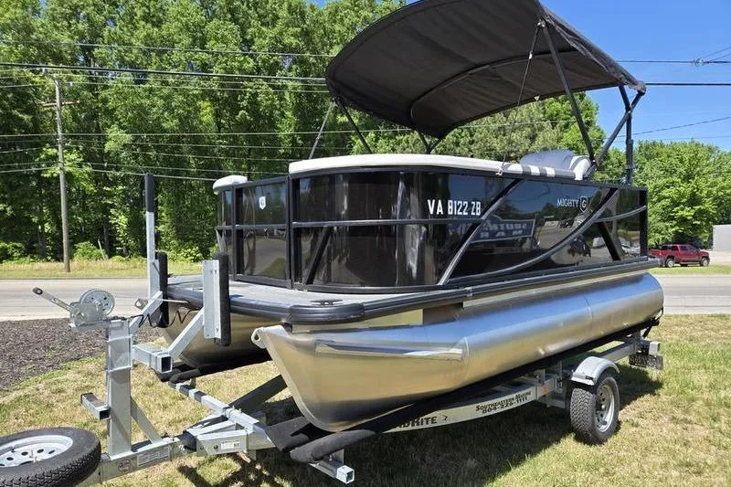 The Image of 2024 Godfrey Mighty G 1476 C pontoon boat on trailer, parked outdoors. - 1