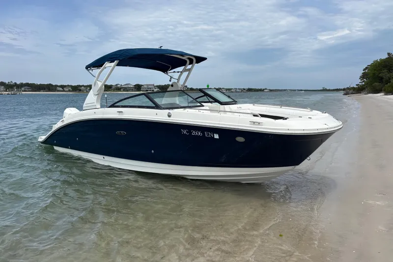 The Image of 2019 Sea Ray SDX 270 Outboard boat beached on a sandy shore under a cloudy sky. - 1
