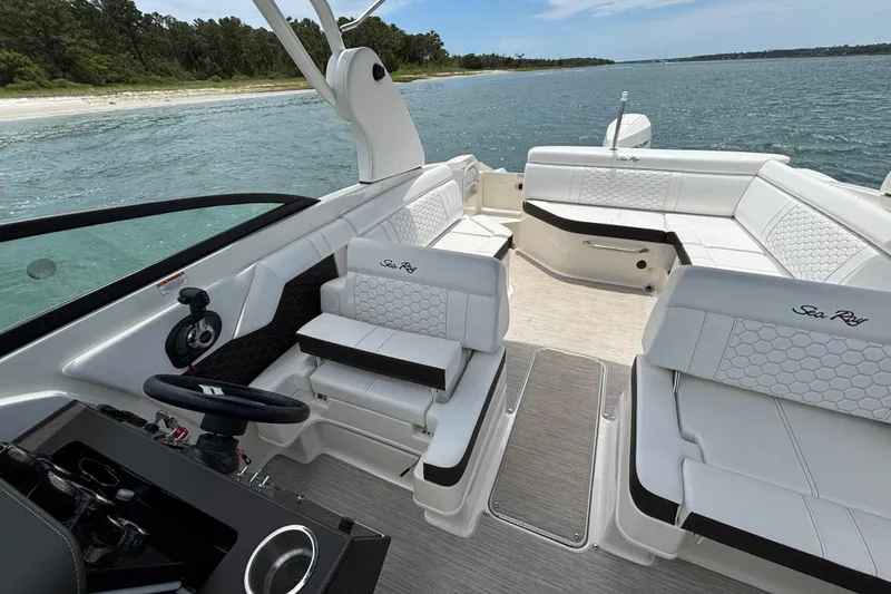 Slide: The Image of 2019 Sea Ray SDX 270 Outboard boat interior with white seating, steering wheel, and scenic water view. - 16