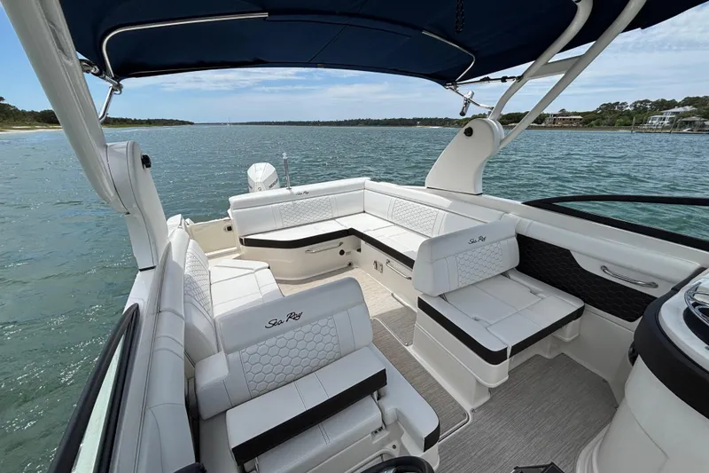 Slide: The Image of 2019 Sea Ray SDX 270 Outboard boat interior with white seating and blue canopy on open water. - 17