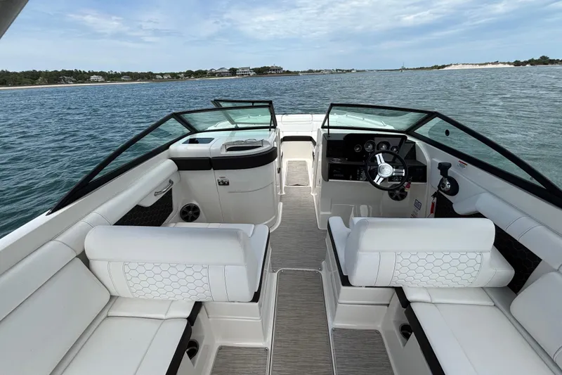 Slide: The Image of 2019 Sea Ray SDX 270 Outboard boat interior with white seating and steering wheel on open water. - 25