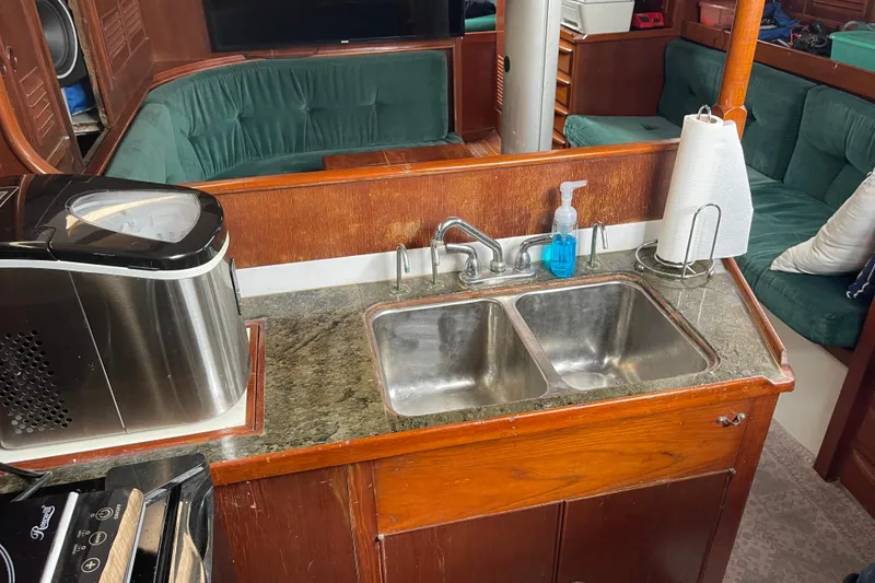 The Image of 1984 TA Chaio CT47 yacht kitchen with double sink, countertop, and seating area. - 1