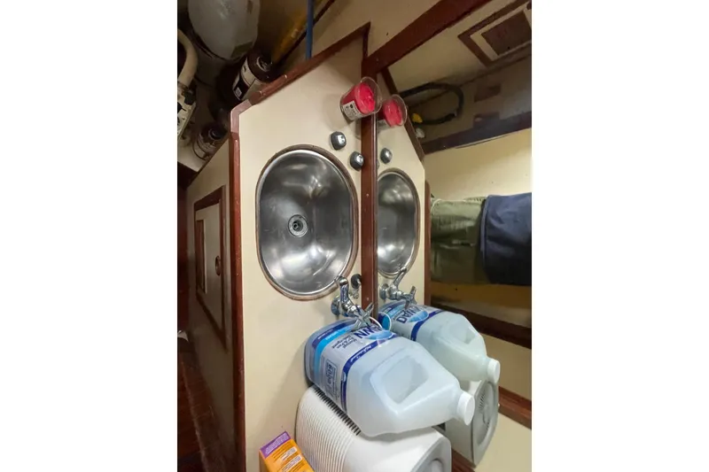 Slide: The Image of Small bathroom sink area in a 1984 TA Chaio CT47 boat, with cleaning supplies. - 18