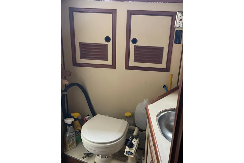 Slide: The Image of Compact boat bathroom with toilet, cleaning supplies, and sink in a 1984 TA Chaio CT47. - 23