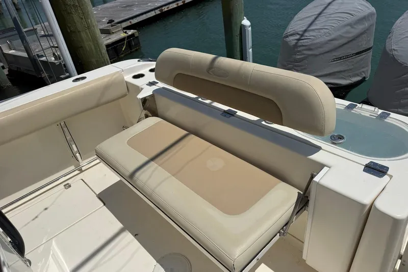 Slide: The Image of 2015 Cobia 296 Center Console boat seating area with beige cushions at dock. - 7
