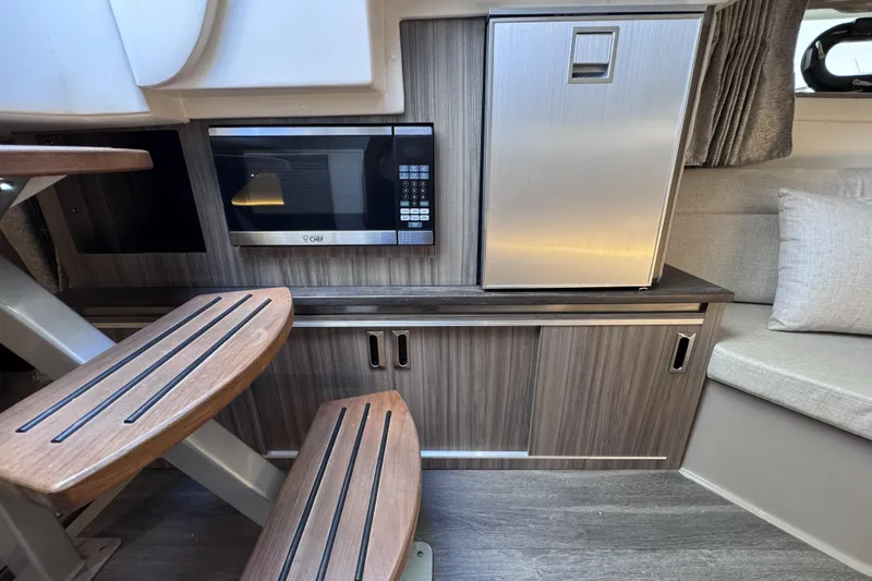 Slide: The Image of 2021 Sea Ray Sundancer 320 interior with microwave, fridge, and wooden steps. - 12