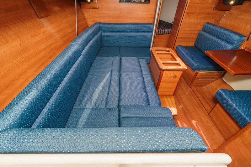 Slide: The Image of Interior of 2015 Hunter 33 sailboat with blue cushioned seating and wooden accents. - 14