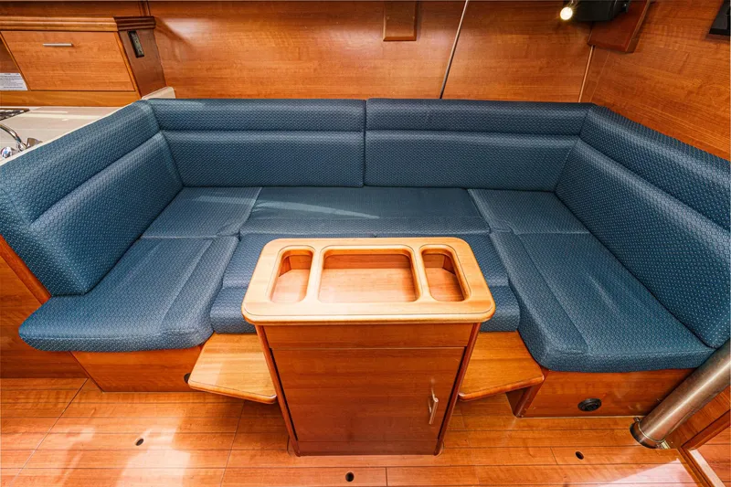 Slide: The Image of 2015 Hunter 33 yacht interior with blue cushioned seating and wooden table. - 16
