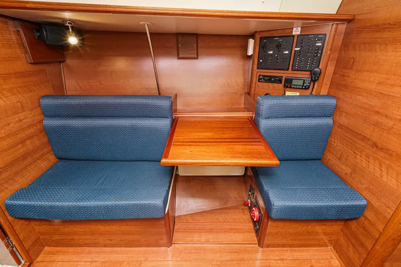 Slide: The Image of 2015 Hunter 33 yacht interior with wooden table and blue cushioned seating. - 18