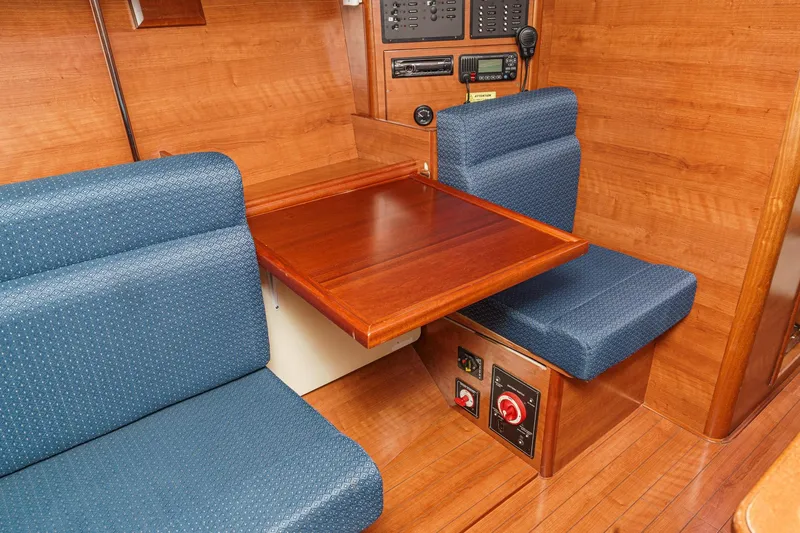 Slide: The Image of Interior of 2015 Hunter 33 sailboat with wooden table and blue cushioned seating. - 20