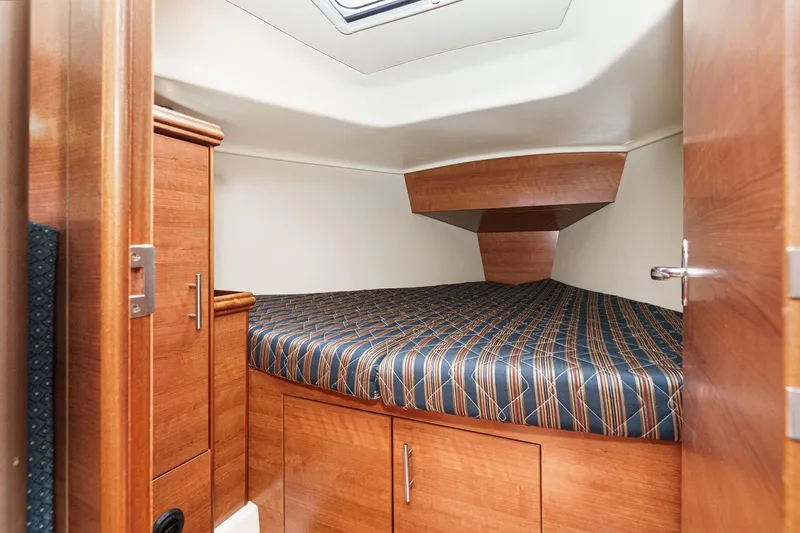 Slide: The Image of 2015 Hunter 33 yacht cabin with wood finish and striped bedding. - 21