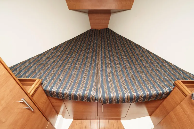 Slide: The Image of 2015 Hunter 33 yacht interior with patterned bed and wooden cabinetry. - 22