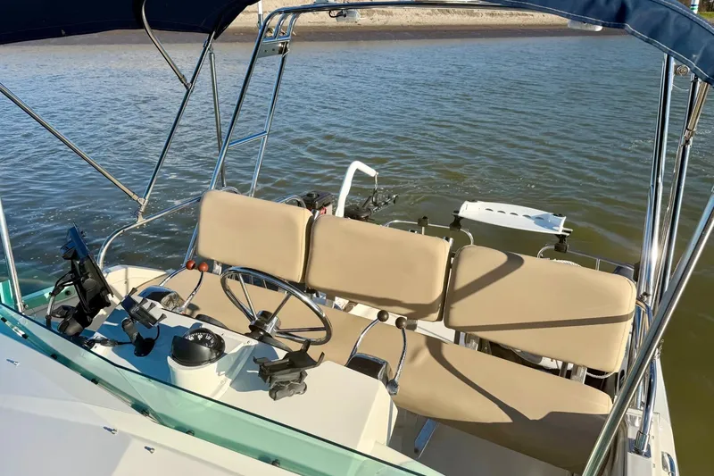 Slide: The Image of 1981 Bertram 28 Flybridge Cruiser helm with beige seating and steering wheel on calm water. - 11