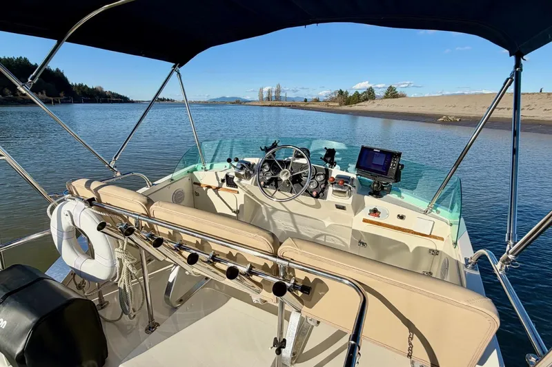 Slide: The Image of 1981 Bertram 28 Flybridge Cruiser on calm water, featuring helm and fishing rod holders. - 13