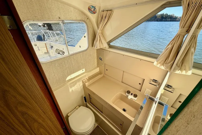 Slide: The Image of Interior of 1981 Bertram 28 Flybridge Cruiser, featuring compact bathroom with window view. - 16