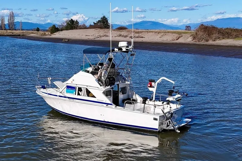 Slide: The Image of 1981 Bertram 28 Flybridge Cruiser on calm water, scenic background. - 2