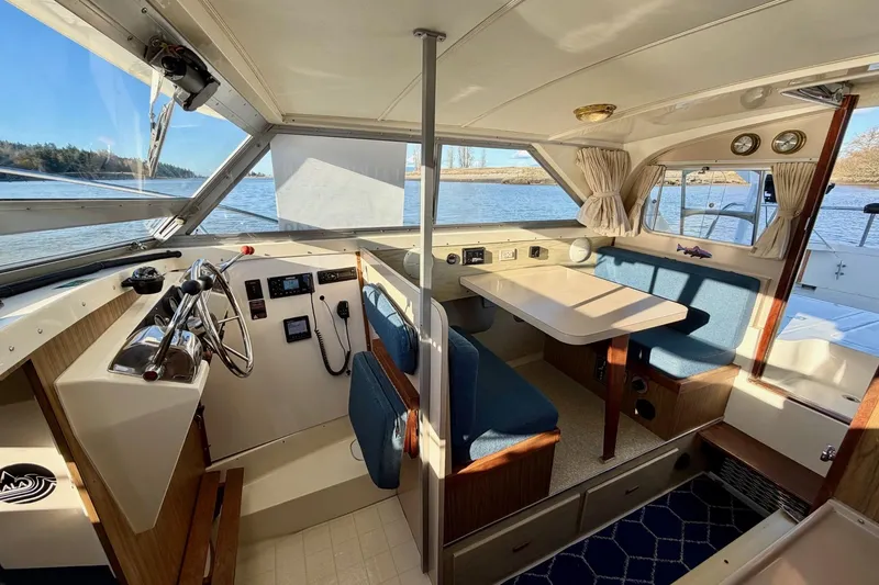 Slide: The Image of 1981 Bertram 28 Flybridge Cruiser interior with helm, seating, and dining area, overlooking water. - 22